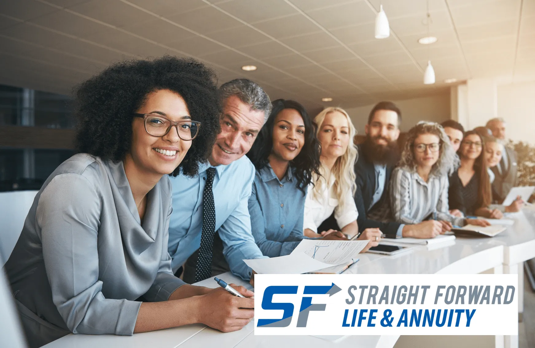 A smiling team of advisors seated at a conference table, with the Straight Forward Life & Annuity logo